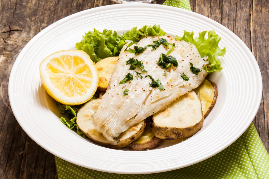 Prato de bacalhau assado com ervas, batata, rodelas de limão e alface