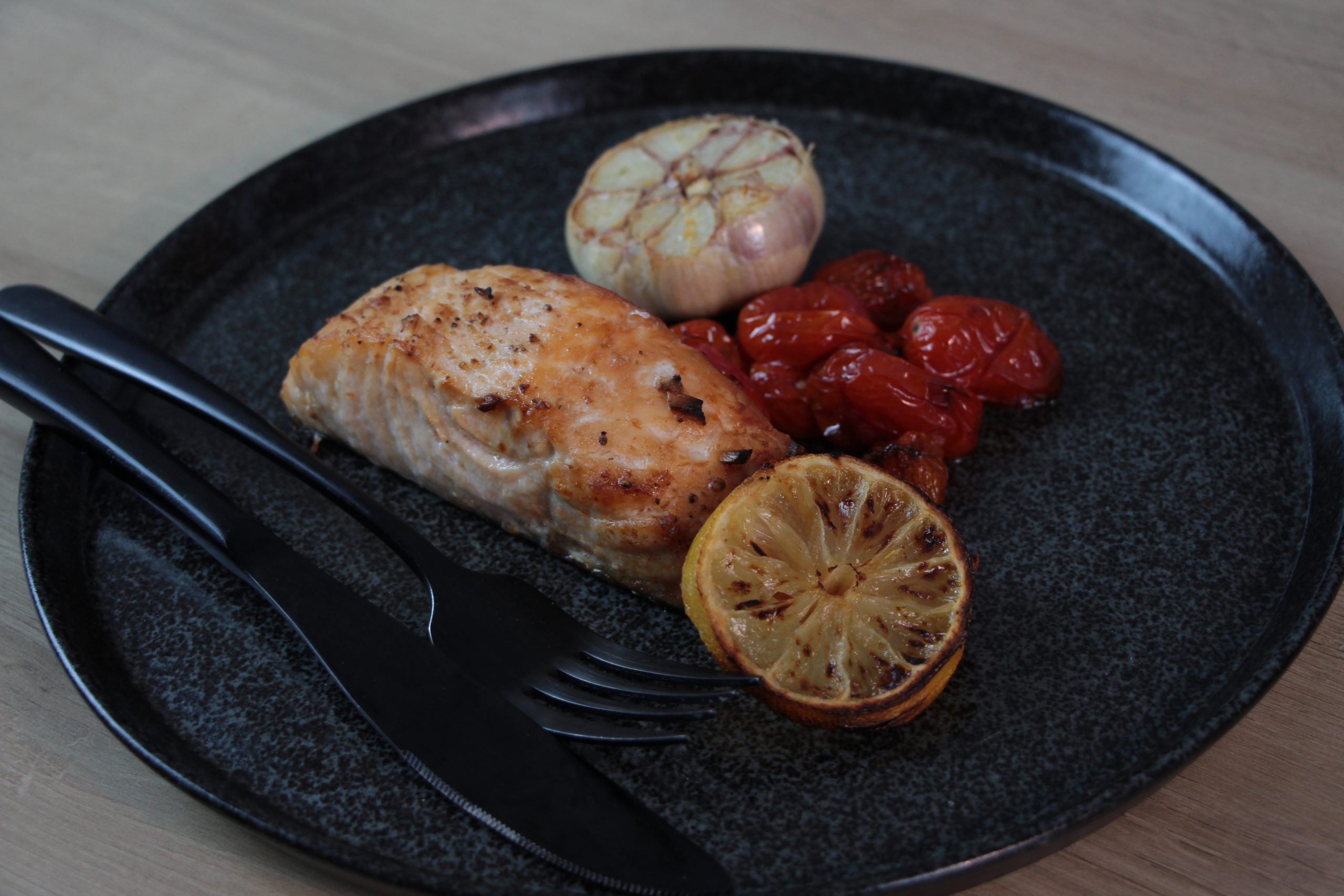 Receita de salmão grelhado feita na Air Fryer, exposta no prato com limão tomates cereja.